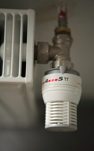 Un thermostat avec de billet autour. Image de l'augmentation des frais de chauffage et par la suite la motivation d'investir dans de l'énergie renouvellable ou de consommer moins.